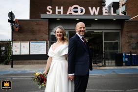 In front of Shadwell Tube Station in London, a couple stands close together for a city-inspired portrait that blends modern urban life with classic romance.